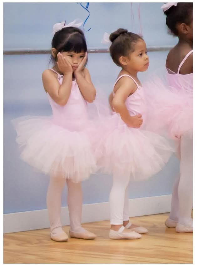 Young ballet students in pink tutus waiting during class